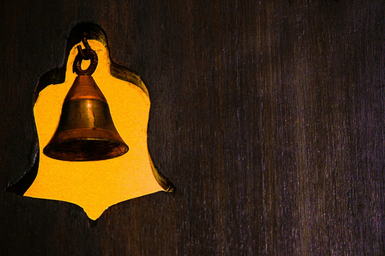 A brass bell hanging on a wooden surface